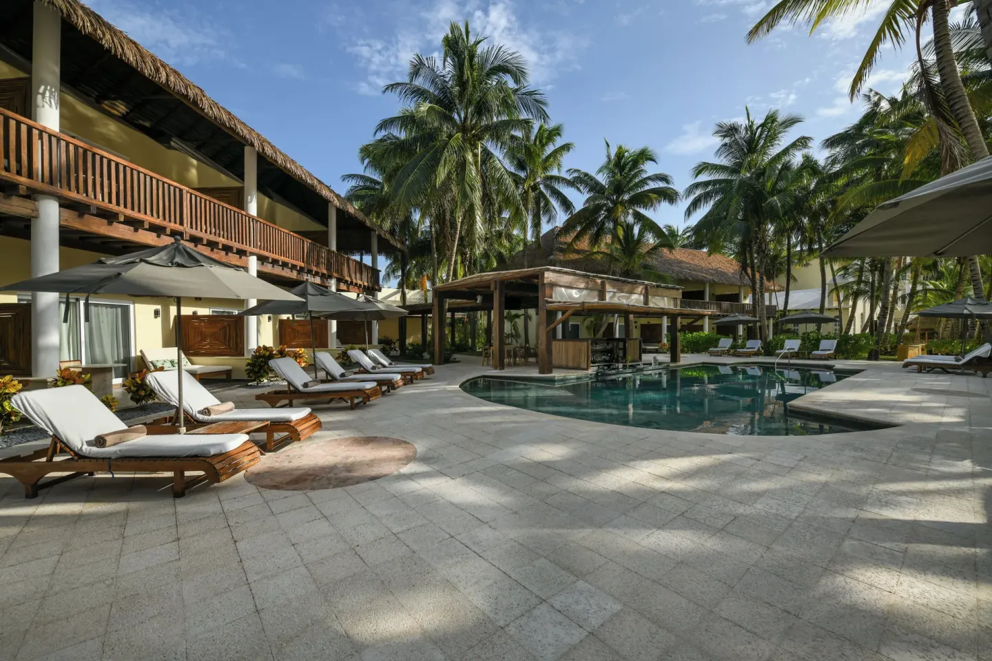 Courtyard pool with loungers and palms at El Dorado Maroma Cenote, Underground Expedition.