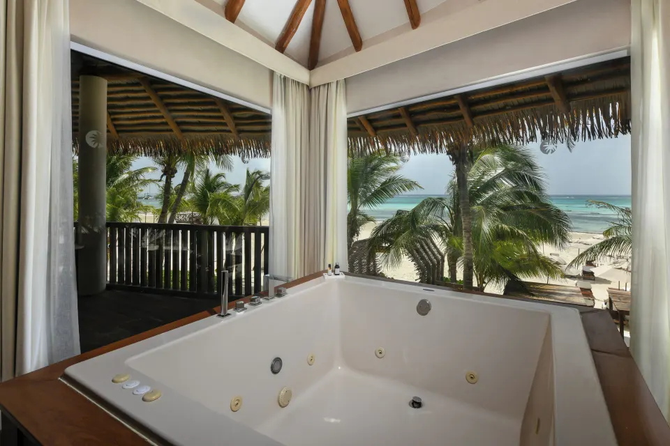 In-room whirlpool tub beside windows with ocean views at El Dorado Maroma Cenote, Underground Expedition.