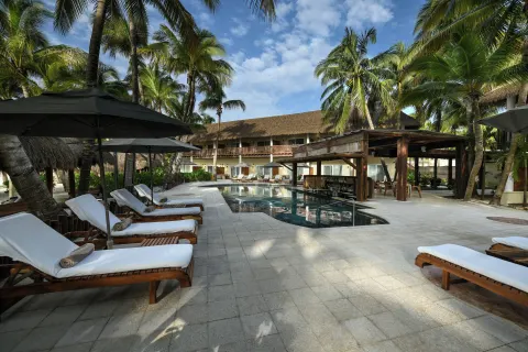 Palm-shaded pool deck with loungers at El Dorado Maroma Cenote, Underground Expedition.