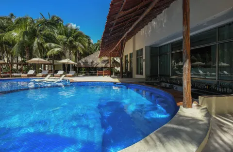 Pool with swim-up bar and palms at El Dorado Maroma Cenote, Underground Expedition.