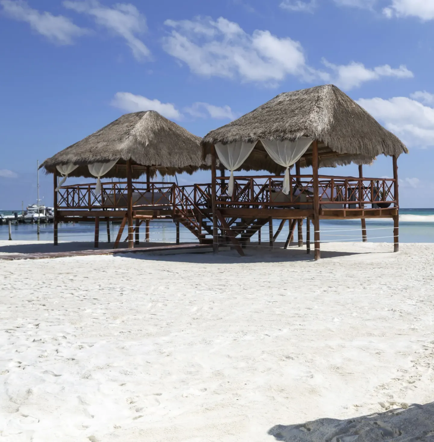 Thatched beach palapas stand by the water at El Dorado Maroma Cenote, Underground Expedition.