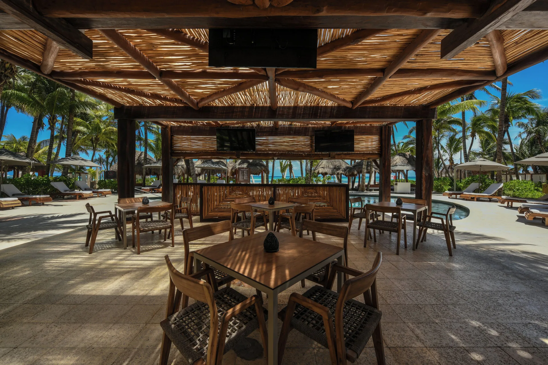 Open-air poolside bar seating at El Dorado Maroma Cenote, Underground Expedition.