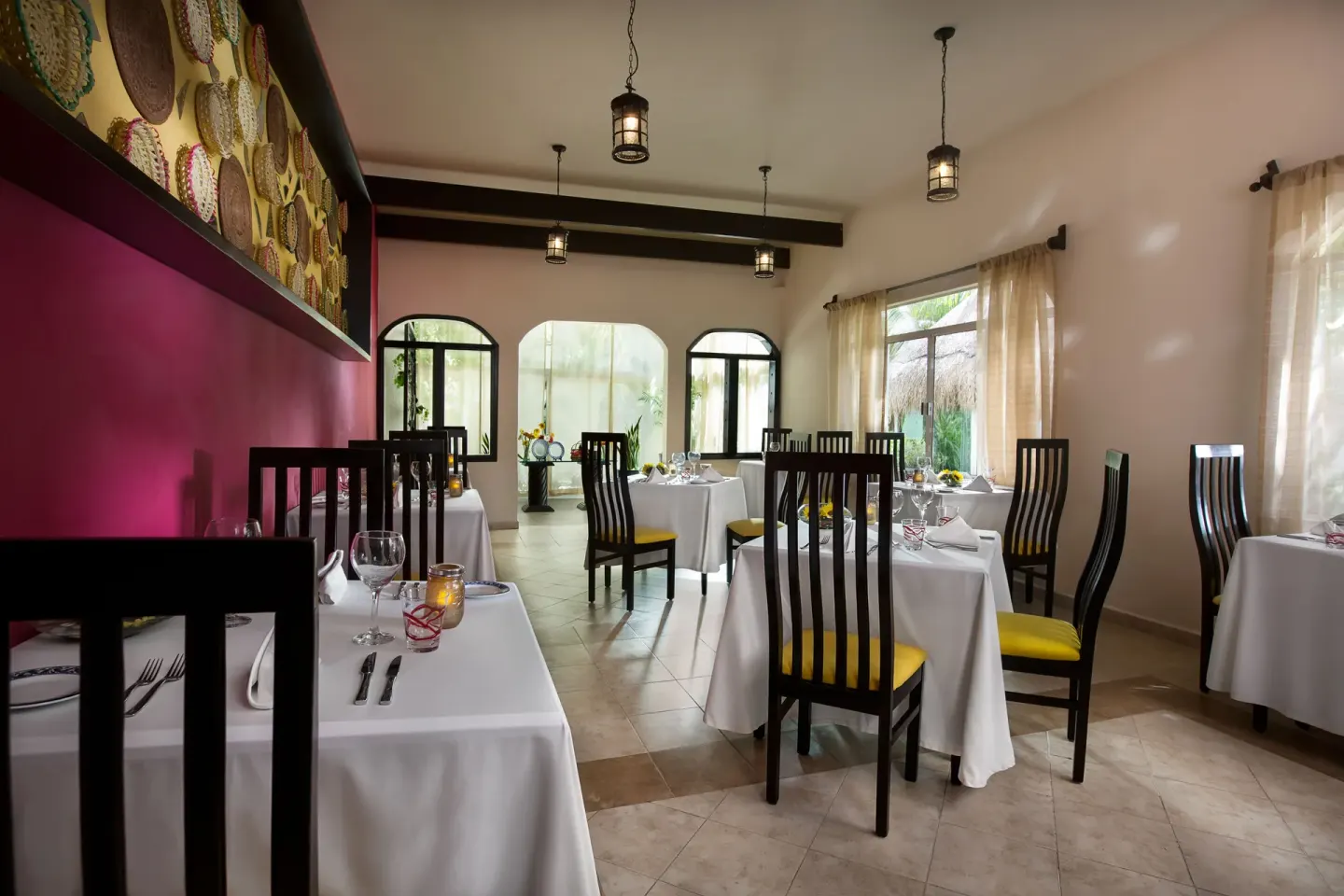 White-tablecloth dining room with magenta wall at El Dorado Maroma Cenote, Underground Expedition.