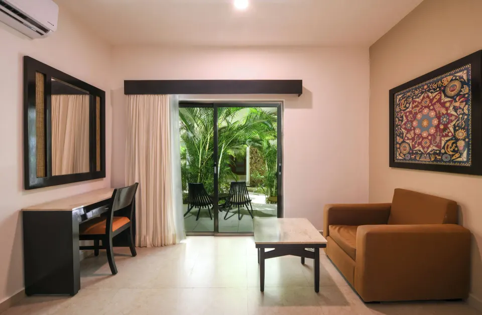 Junior Suite sitting area with sofa and terrace doors at El Dorado Maroma Cenote, Underground Expedition.