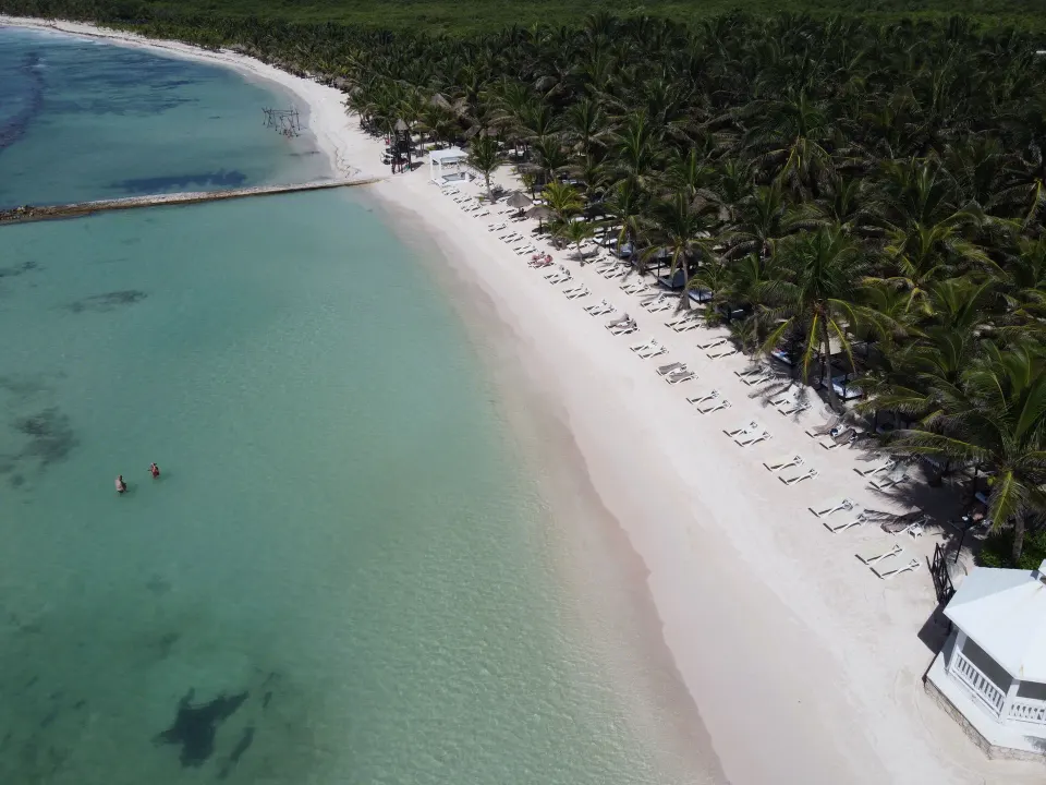 Aerial view of tranquil turquoise bay and lined beach loungers at El Dorado Seaside Suites