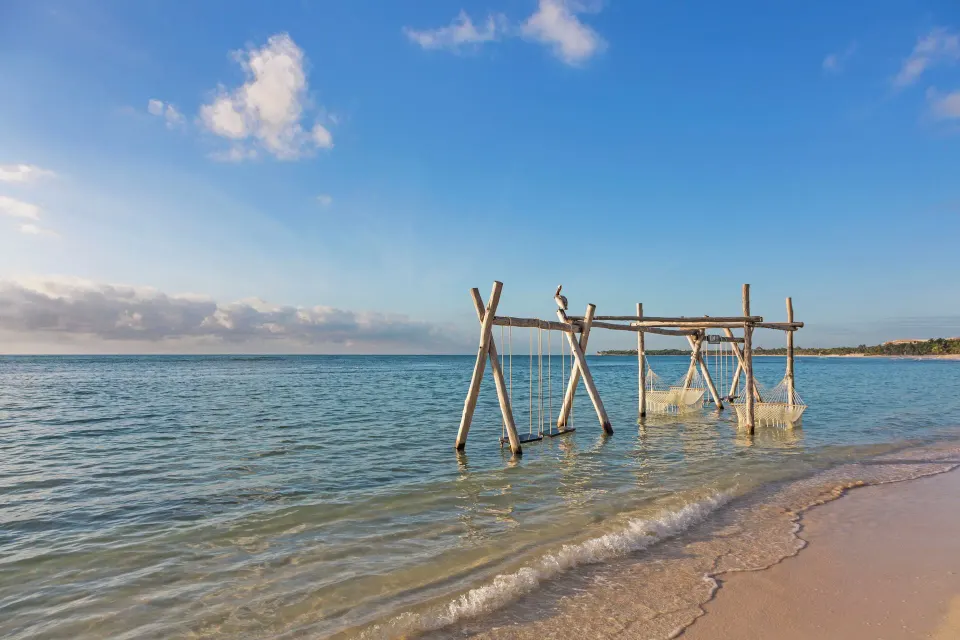 Wooden swing frames set in shallow water on the beach at El Dorado Seaside Suites