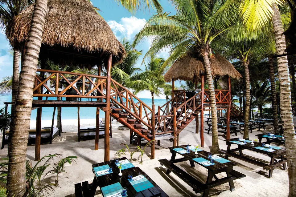 Beachfront palapa dining platforms and picnic tables on the sand at El Dorado Seaside Suites