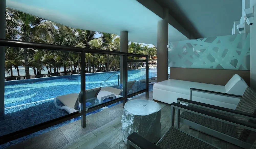 Private balcony overlooking pool with in-pool loungers at El Dorado Seaside Suites