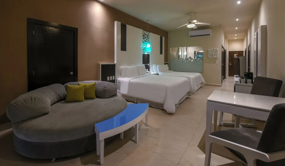 Junior suite at El Dorado Seaside Suites with two beds, seating area, and desk