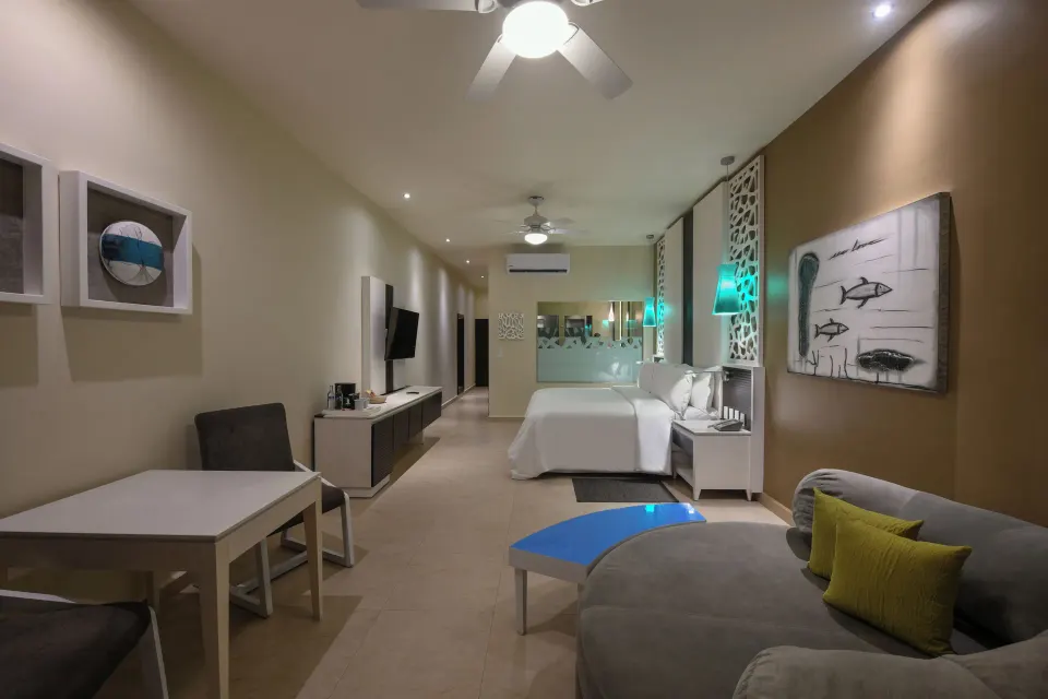 Long view of a junior suite at El Dorado Seaside Suites showing beds, dining table, and TV