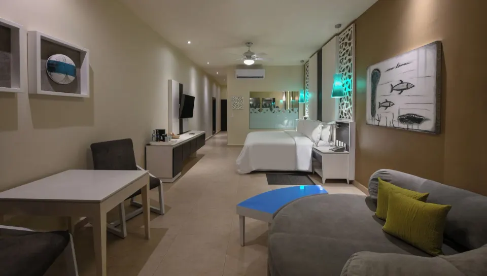Wide interior view of a junior suite at El Dorado Seaside Suites with seating and artwork