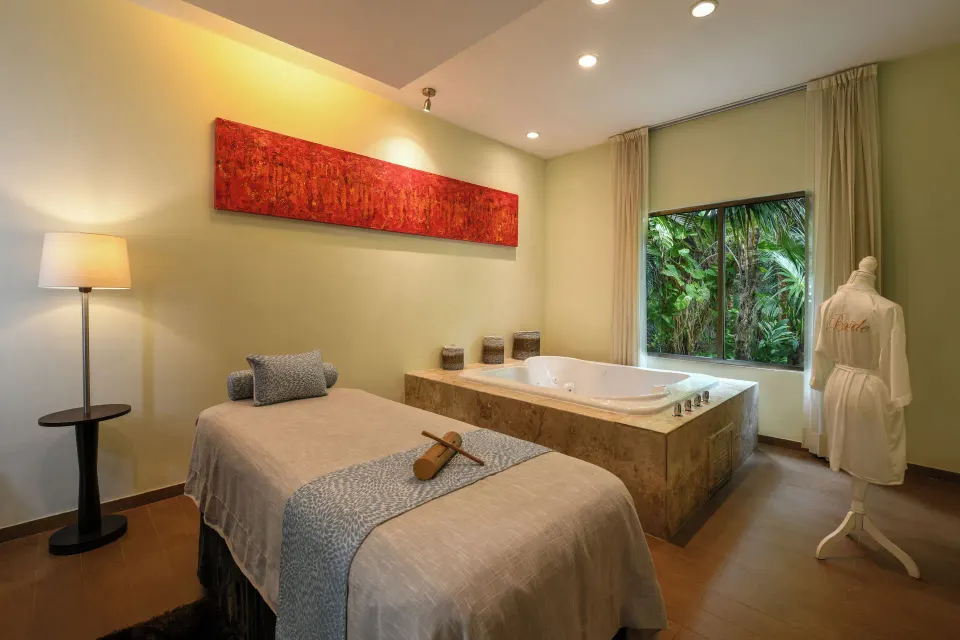 Spa treatment room with massage table and tub at El Dorado Seaside Suites