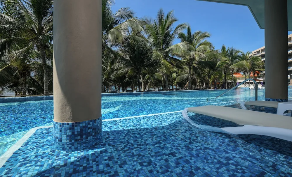 Swim-up pool area with submerged loungers and columns at El Dorado Seaside Suites