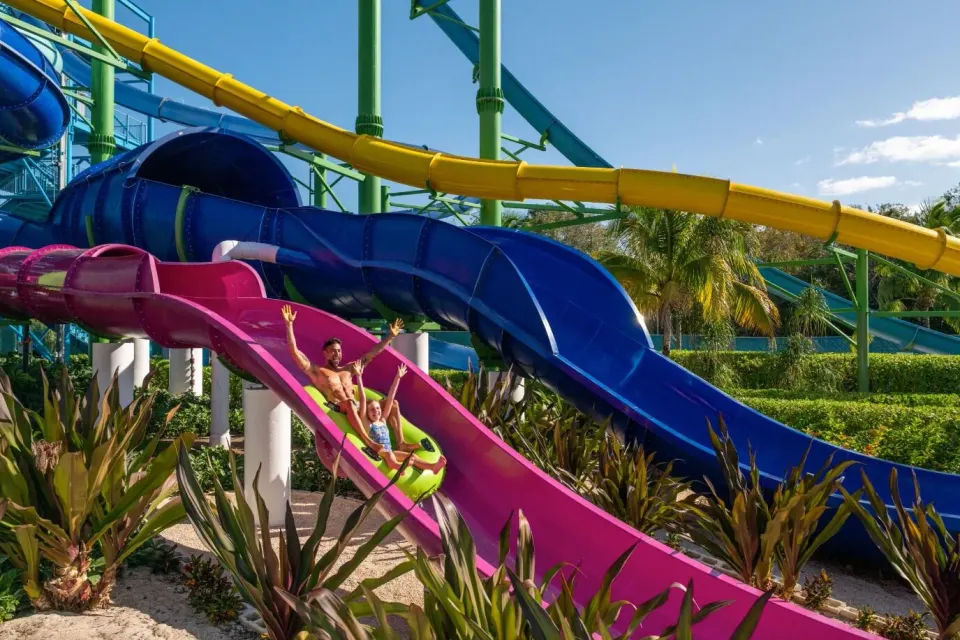 Guests riding a colorful water slide at El Dorado Seaside Suites