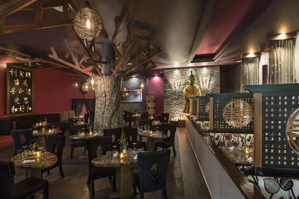 Intimate dimly lit Asian-inspired dining room with decorative screens at El Dorado Seaside Suites