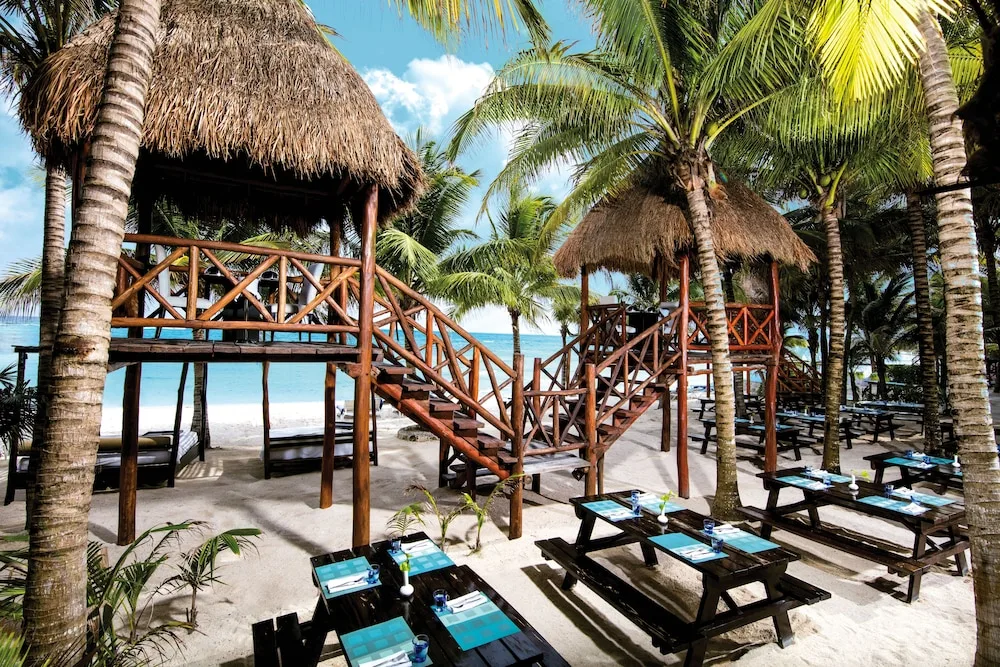 Outdoor beachfront dining under palapas with picnic-style tables at El Dorado Seaside Suites