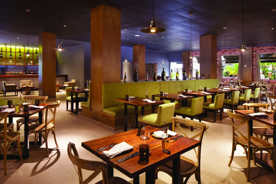 Contemporary indoor dining room with booths and wood tables at El Dorado Seaside Suites