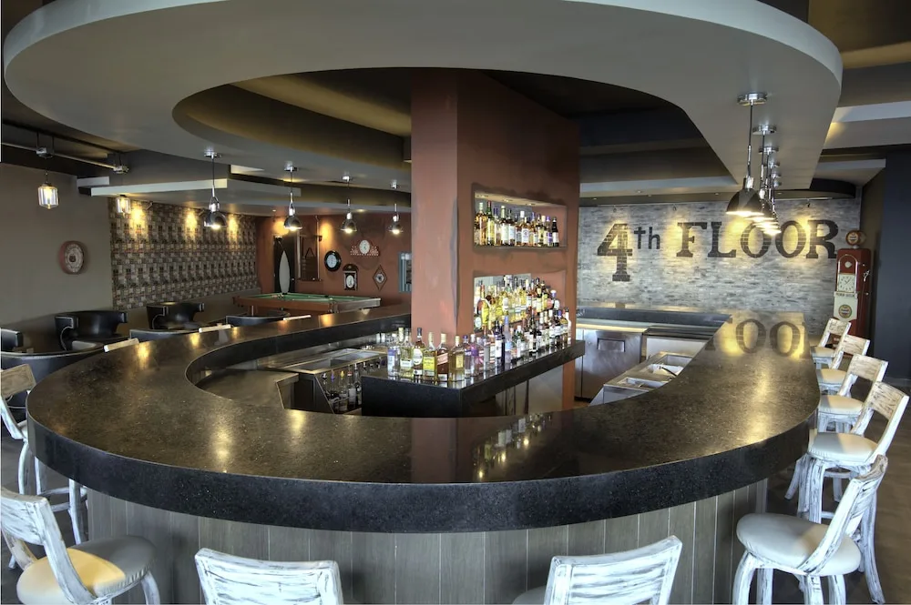 Curved indoor bar with central counter and seating at El Dorado Seaside Suites.