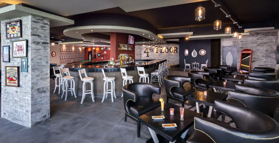 Lounge-style bar area with leather chairs and a curved counter at El Dorado Seaside Suites