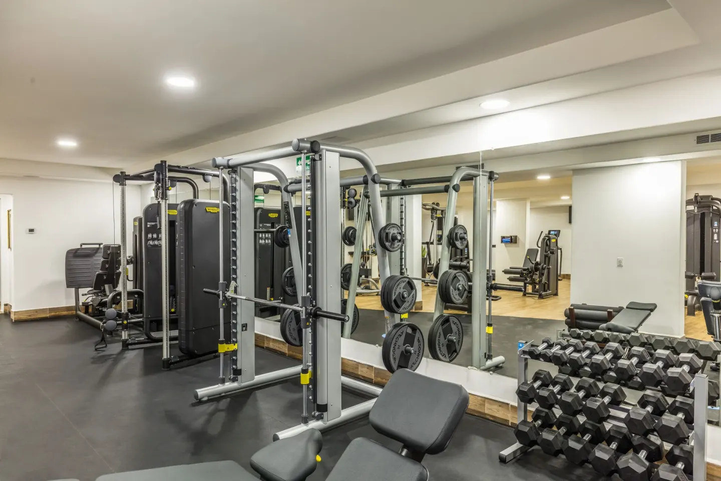 Fitness center with weight machines, benches, and dumbbells at El Encanto at Hacienda Encantada.
