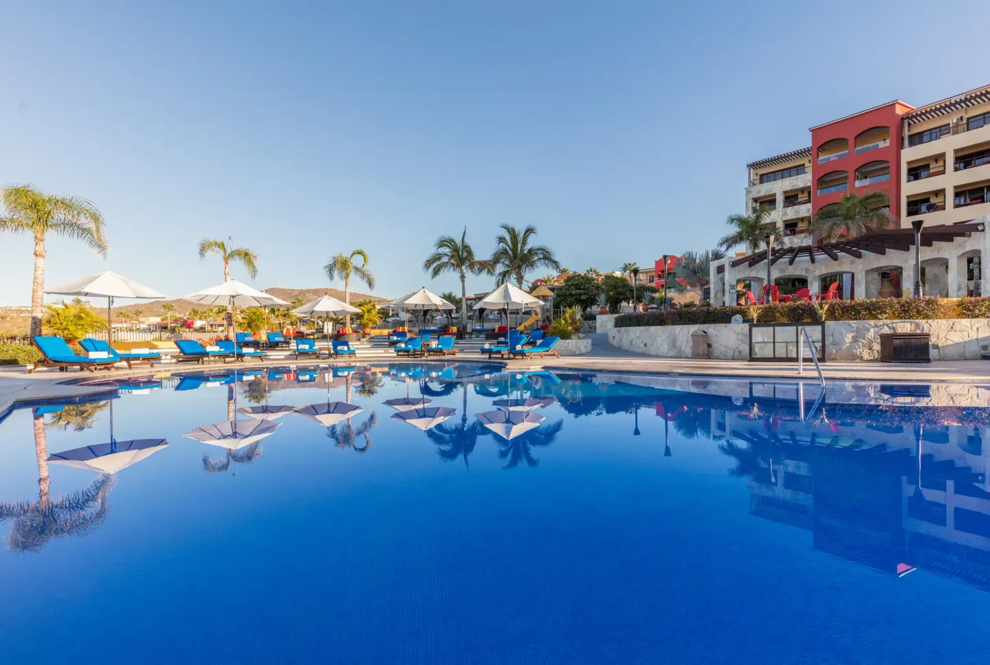 Main resort pool with umbrellas, loungers, and palm trees at El Encanto at Hacienda Encantada.