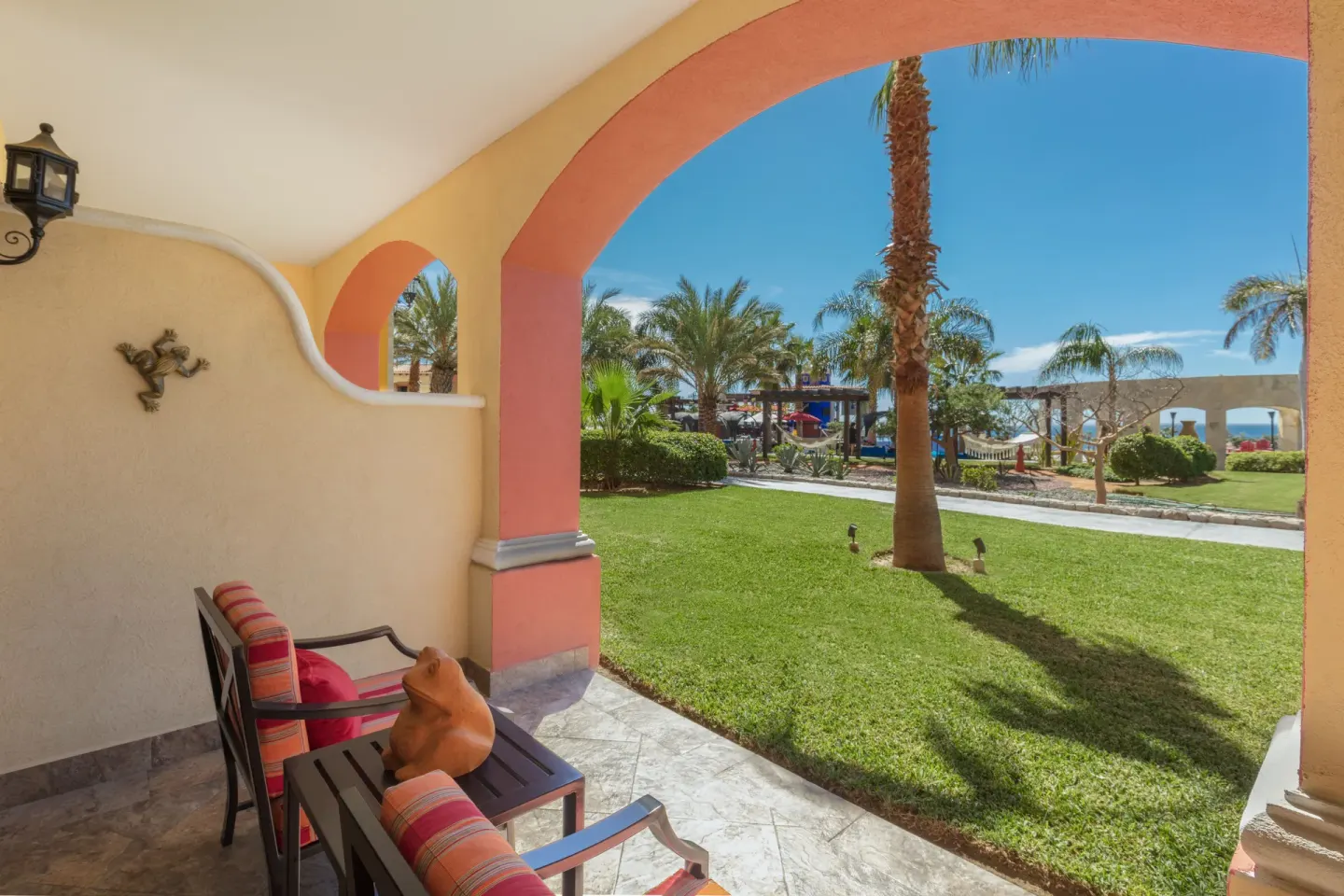 Studio Garden View arched patio with chairs and palm lawn at El Encanto at Hacienda Encantada.