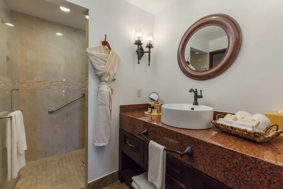Studio Garden View bathroom sink, robe, and tiled shower at El Encanto at Hacienda Encantada.