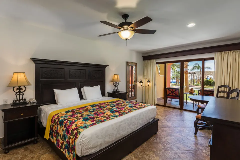 Studio Garden View king bed beside sliding doors and a patio at El Encanto at Hacienda Encantada.