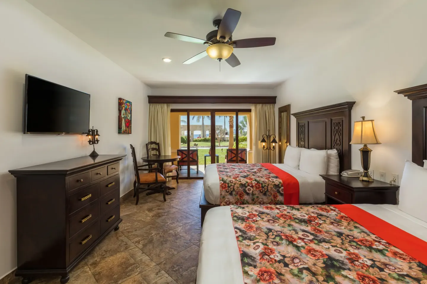 Studio Garden View two beds with dresser, TV, and patio doors at El Encanto at Hacienda Encantada.