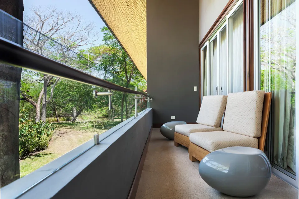 Balcony seating with two chairs and glass railing at El Mangroove Papagayo