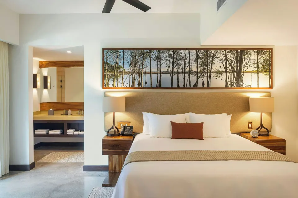 Deluxe room with king bed and open bathroom vanity at El Mangroove Papagayo