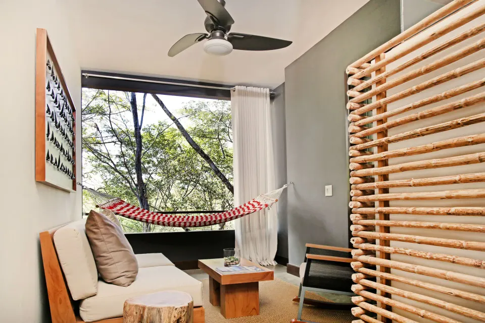 Guest room seating area with hammock and forest view at El Mangroove Papagayo