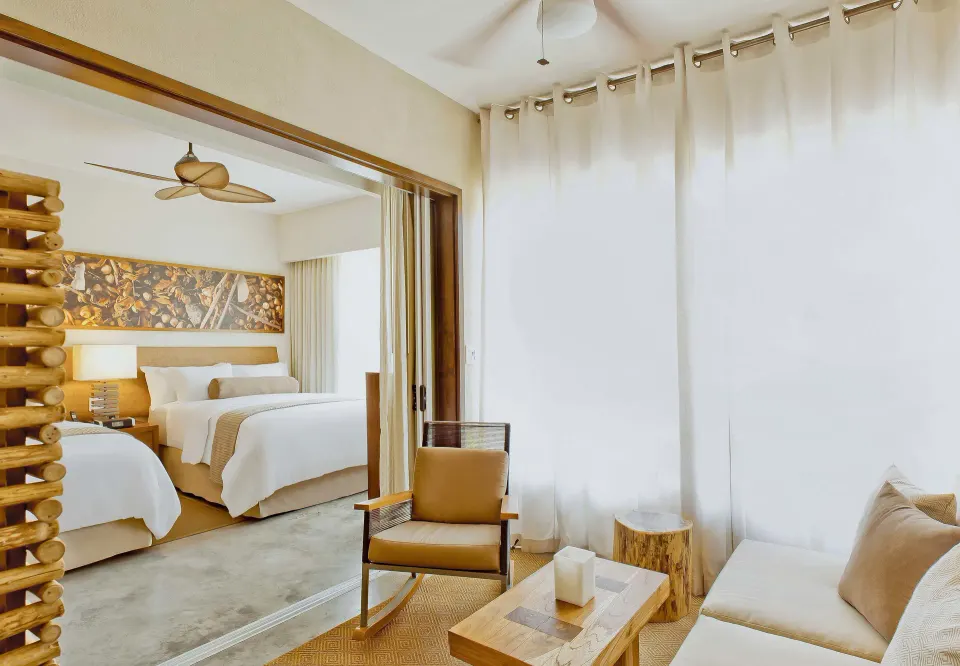 Living area and king bed in a suite at El Mangroove Papagayo with light curtains