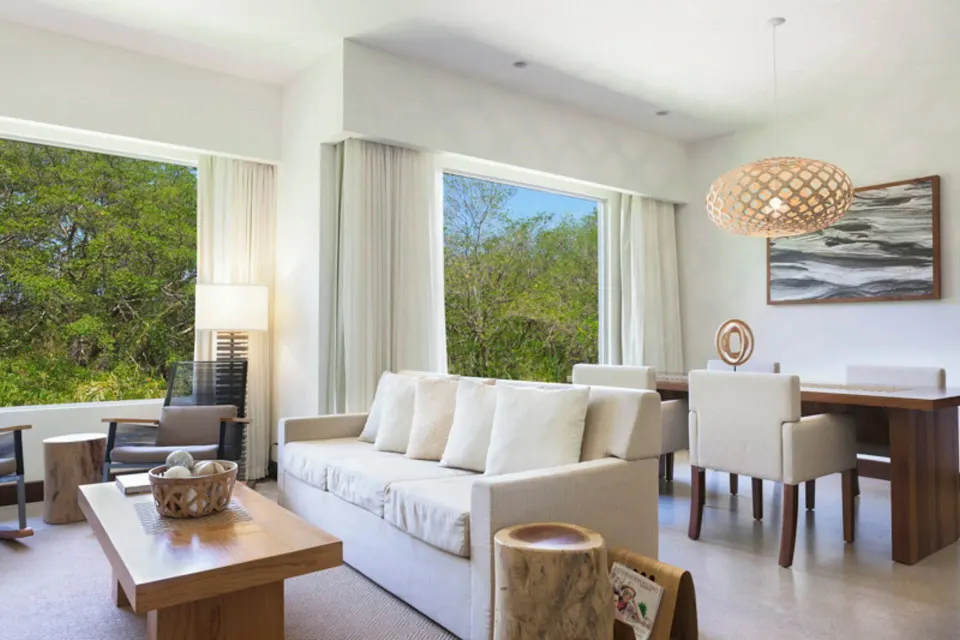 Sofa and dining nook overlooking trees at El Mangroove Papagayo