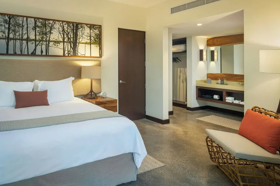 King bed with bedside lamps and open vanity area at El Mangroove Papagayo