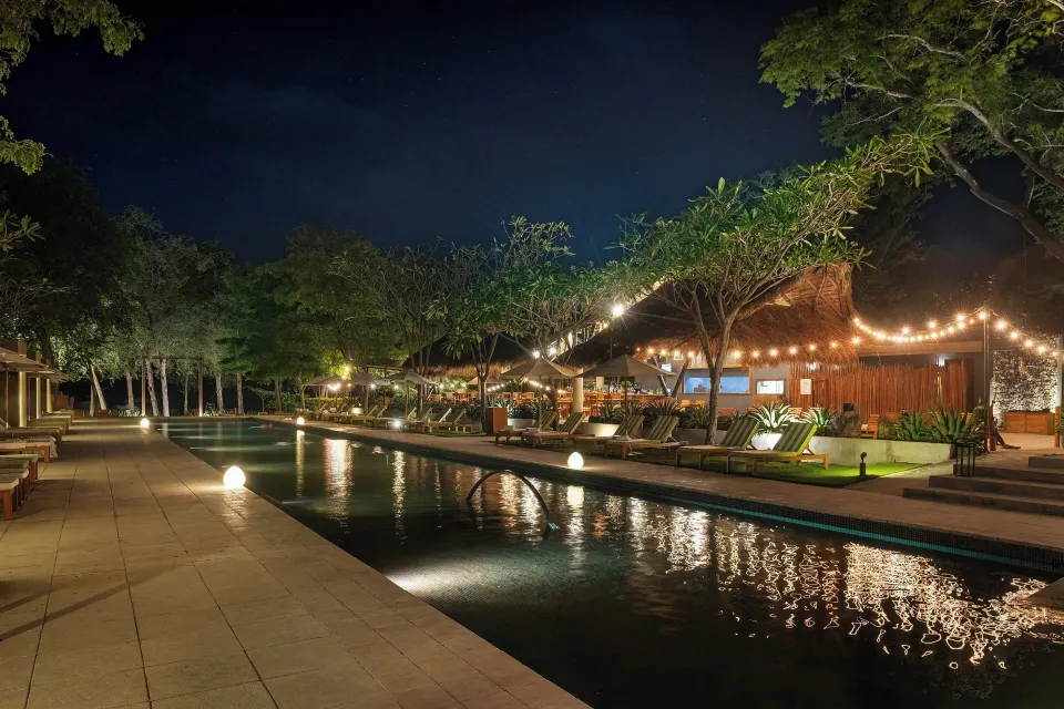 Night view of illuminated pool and string lights along the deck at El Mangroove Papagayo