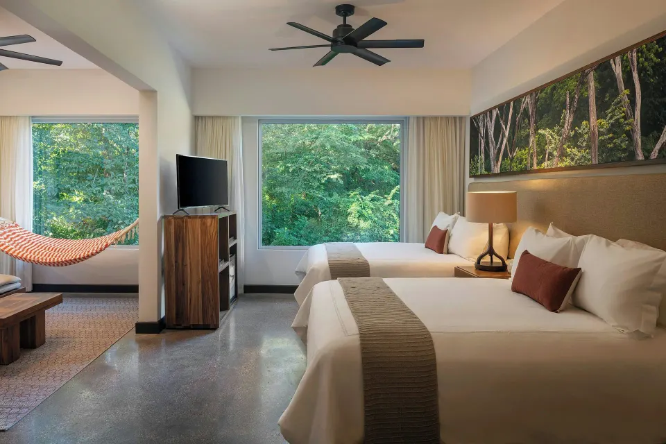 Guest room with two beds, TV and hammock at El Mangroove Papagayo