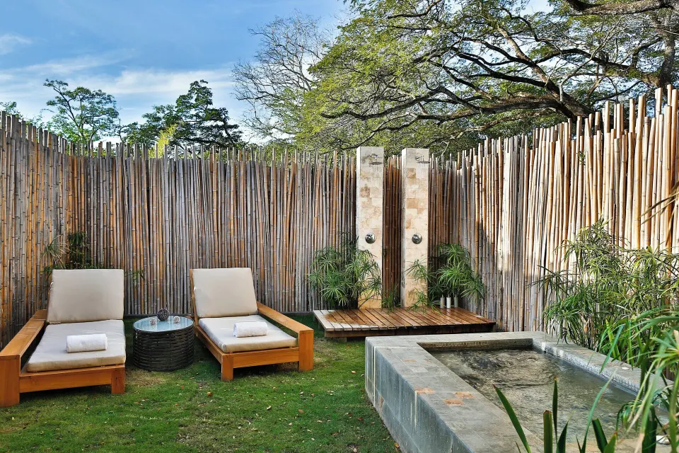 Outdoor spa area with lounge chairs, outdoor showers and a stone water feature at El Mangroove Papagayo