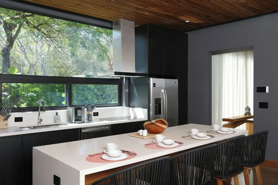 Modern kitchen island with bar seating and garden views at El Mangroove Papagayo