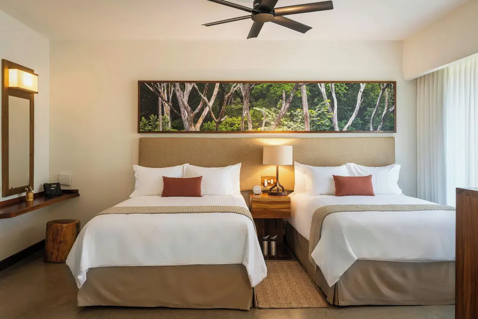 Guest room with two beds and artwork at El Mangroove Papagayo