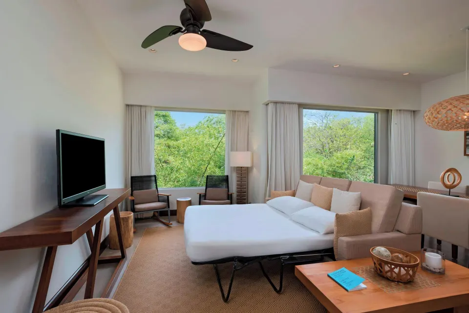 Guest room with sofa bed pulled out and forest views from windows at El Mangroove Papagayo