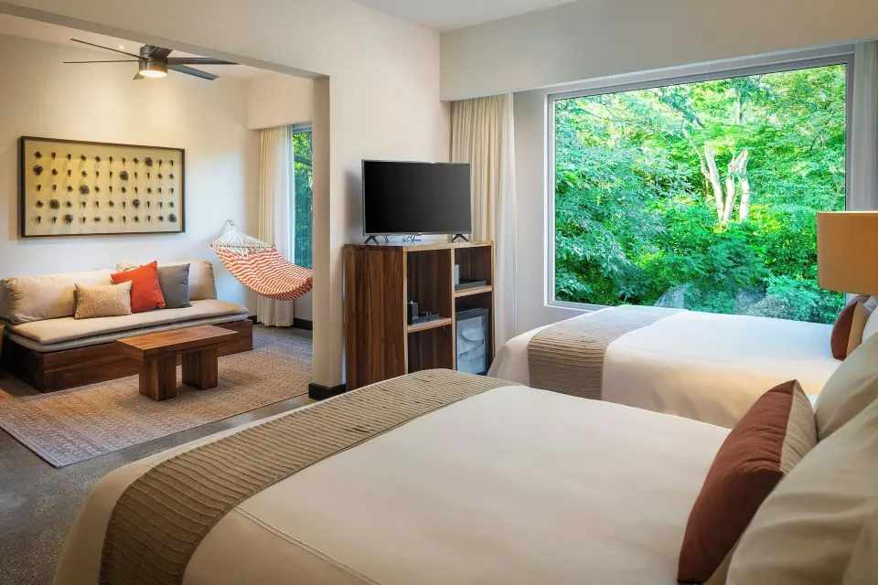 Twin beds with living area, hammock and large forest-view window at El Mangroove Papagayo