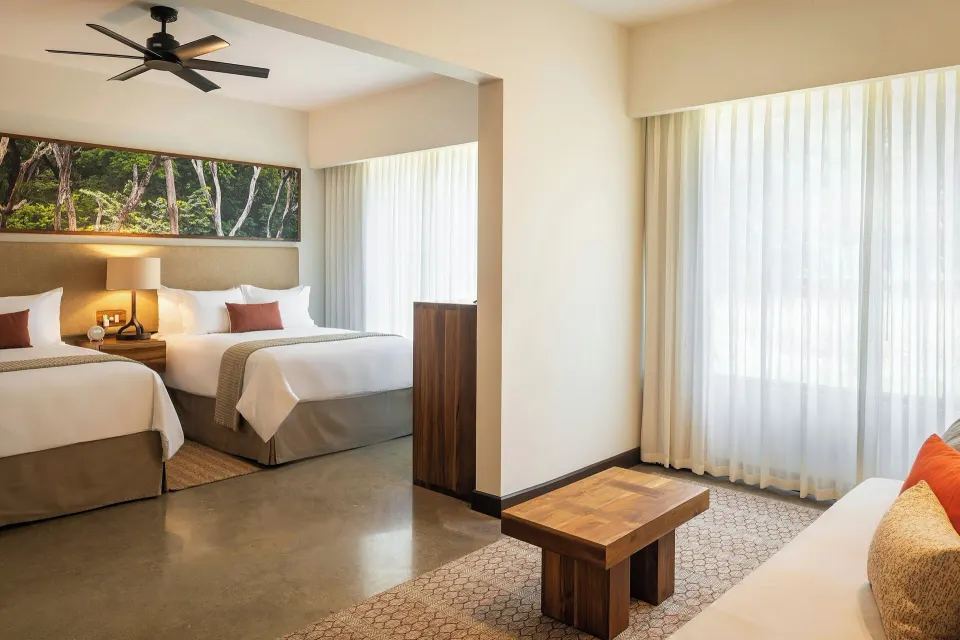 Guest room with two beds and seating area at El Mangroove Papagayo