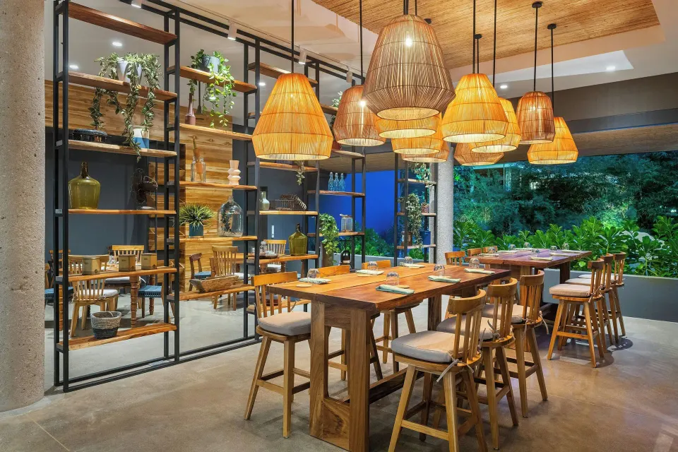 Wood-and-rattan lit dining area with long communal tables at El Mangroove Papagayo