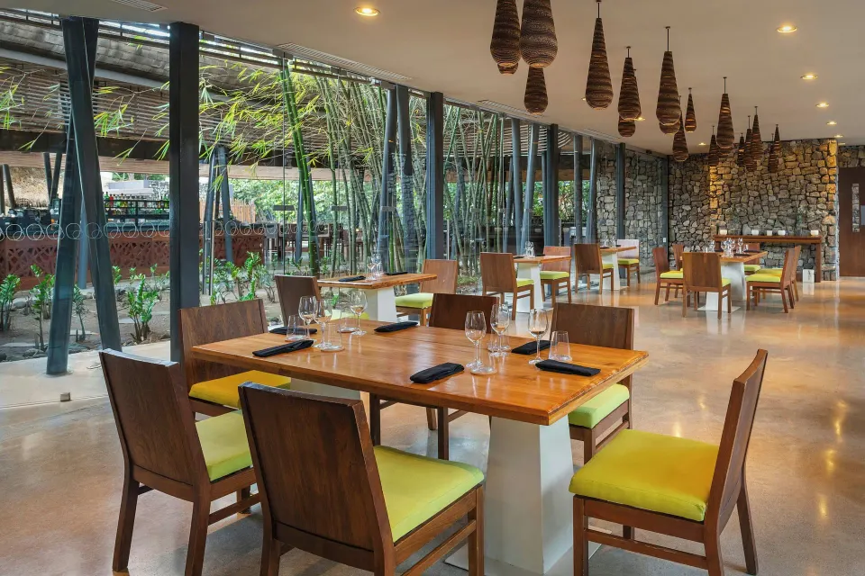 Indoor dining room with wood tables and green-seated chairs at El Mangroove Papagayo