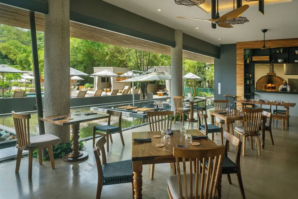 Indoor restaurant seating overlooking poolside loungers and umbrellas at El Mangroove Papagayo