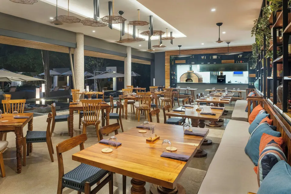 Restaurant interior with rows of wooden tables and cushioned bench seating at El Mangroove Papagayo