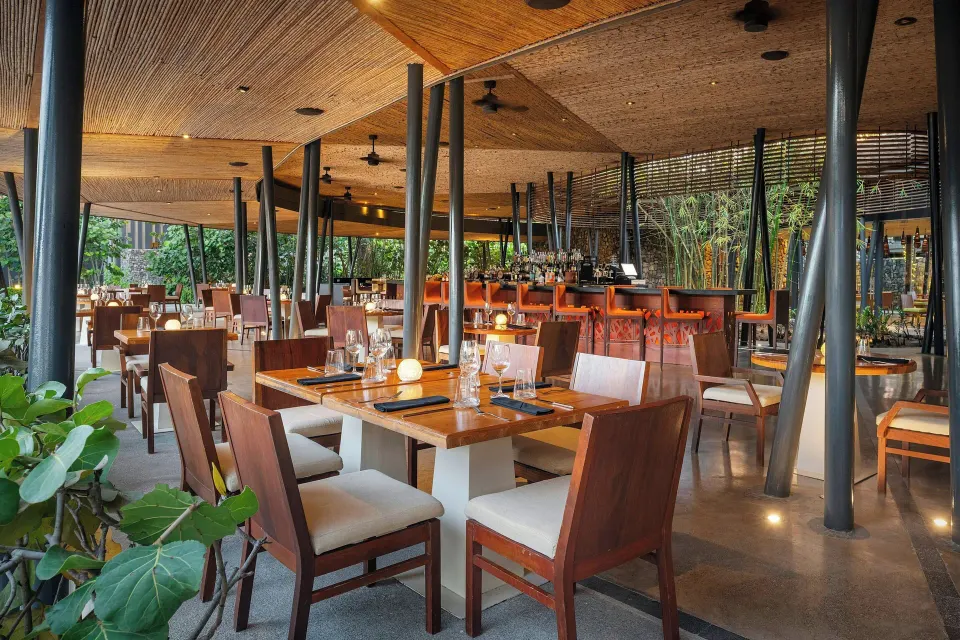 Covered open-air dining with wooden tables and tropical pillars at El Mangroove Papagayo