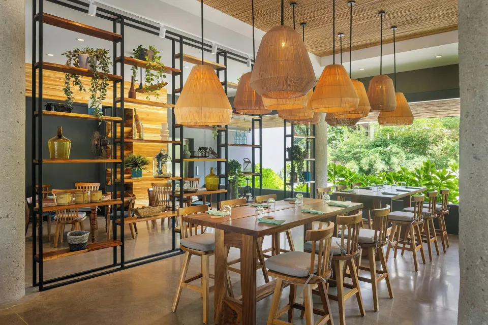 Light-filled open dining area with hanging wicker lamps at El Mangroove Papagayo