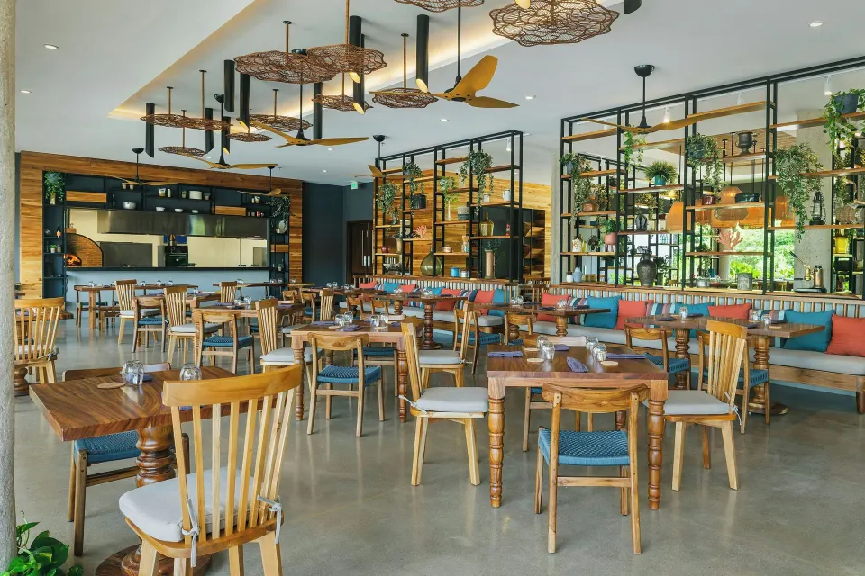 Spacious open-plan restaurant dining room with wooden chairs at El Mangroove Papagayo